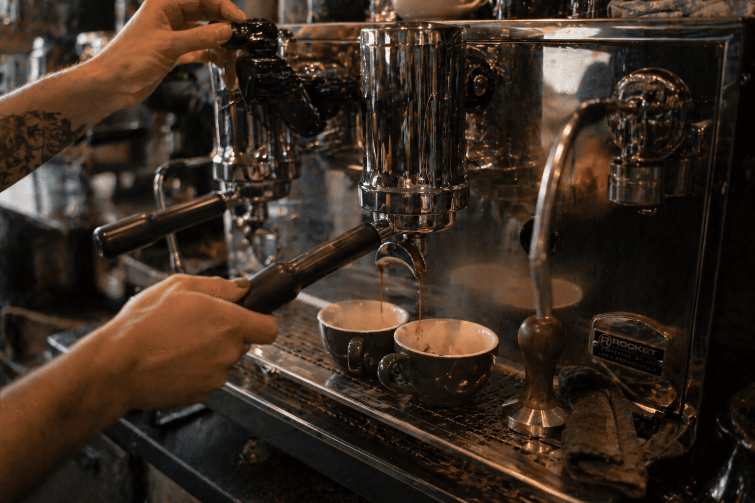 Espresso pulling from a chrome espresso machine into two cups in an independent UK café.