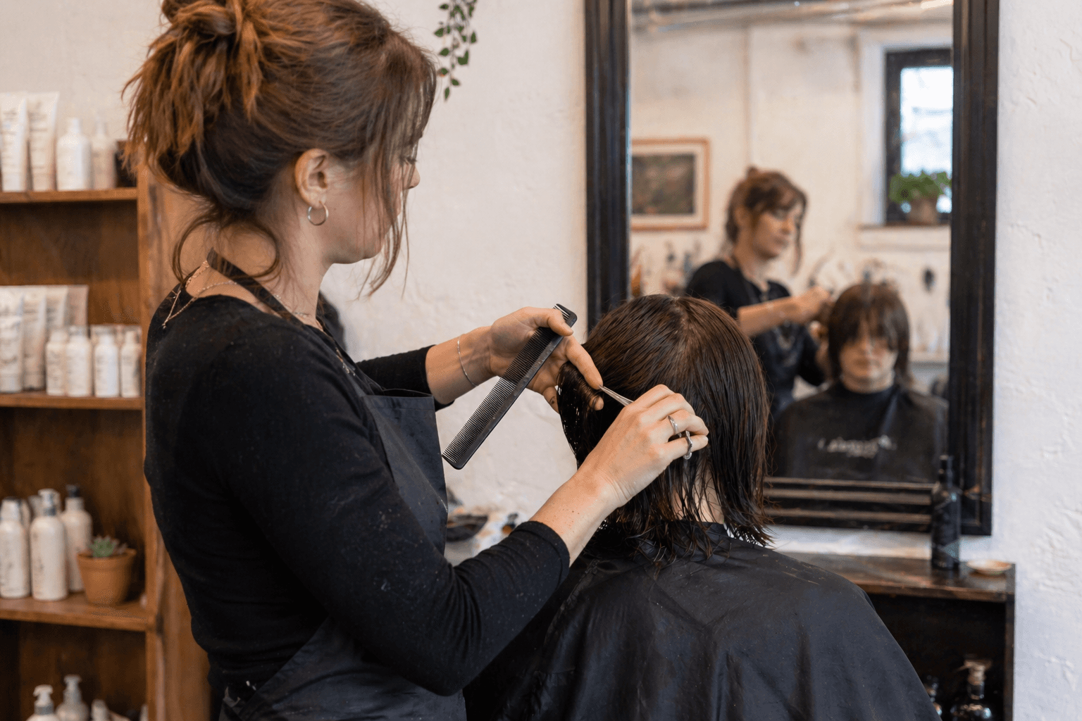 A hairstylist mid-cut at a styling chair inside a small independent UK salon.